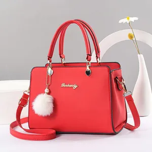 Elegant red faux leather tote bag with top handles, gold hardware, and fur pompom charm