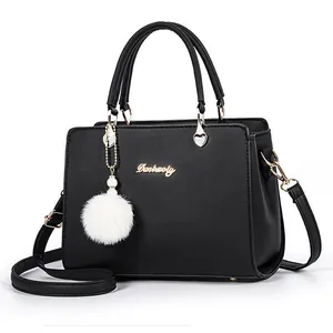 Classic black leather handbag for women with double handles and a white plush pompom charm