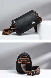 Dettaglio borsa Boston nera motivo coccodrillo con fibbia floreale e tracolla larga