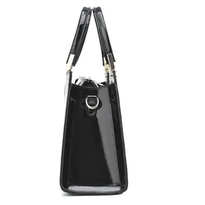 Side view of shiny black patent leather handbag with gold metal hardware and D-rings