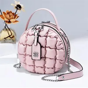 Rosa gesteppte runde Handtasche mit Kettenschultergurt und Kleeblatt-Anhänger im Studio