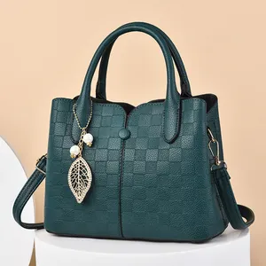 Dark green leather handbag with checkered texture and gold leaf pearl charm detail