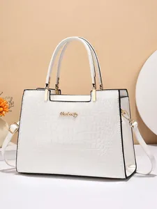 Détail du sac à main blanc motif crocodile avec finitions dorées et logo de la marque