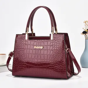 Détails du sac à main en cuir verni bordeaux à motif crocodile et finitions dorées