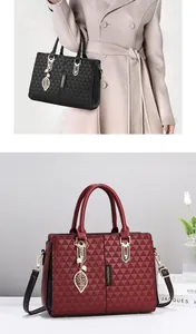 Close-up of elegant leather handbags in black and burgundy with leaf charms and gold hardware