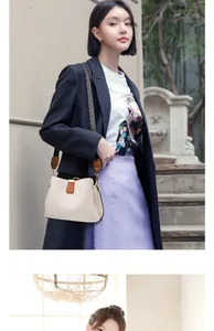 Detail of contrast color bucket bag with wide herringbone strap on a stylish model