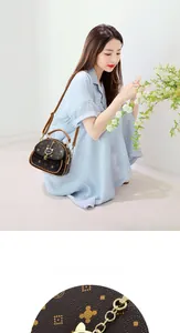 Detail view of small brown crossbody bag with gold flower pattern and cat charm