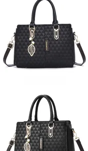 Detail of black pebbled leather tote with geometric embossing and gold leaf pendant