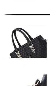 Detailed view of black geometric embossed leather handbag with golden metal D-rings