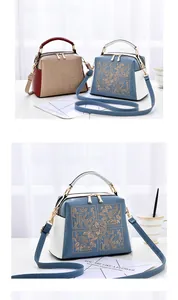 Detail of embroidered floral texture and gold hardware on two-tone crossbody bags