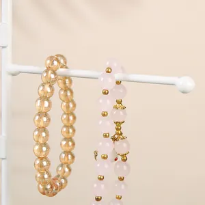 Primer plano de pulseras de cuentas de jade rosa y ámbar en un soporte de metal para joyas