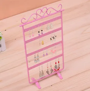 Pink metal 4-tier earring stand with 48 holes showing various jewelry on wood table
