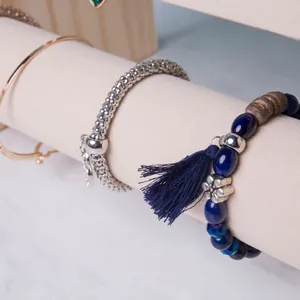 Detailed view of gold and silver bracelets on a white leather jewelry display stand
