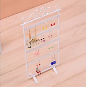 Close-up of white metal earring stand with heart-shaped top and multi-layered hanging holes