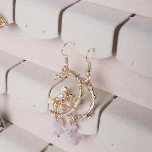 Golden twig hoop earrings with bird detail and purple stone pendant on jewelry display
