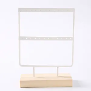 Detail of white metal jewelry rack with wood base showing double-layer earring holes