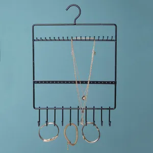 Detail of wall-mounted black iron jewelry organizer with hooks for necklaces and earrings