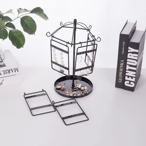 Close-up of a rotating black metal earring holder featuring mesh panels and a tray base