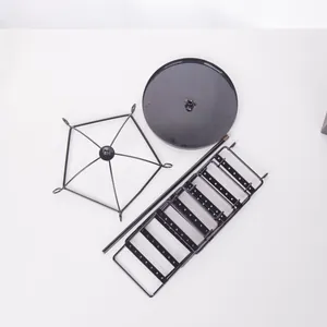 Unassembled components of a black rotating metal jewelry stand with a round base and tiered rack