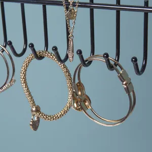 Black iron wall-mounted jewelry rack for necklaces and bracelets on blue background