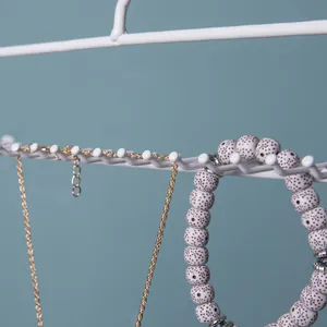 Detail of white metal jewelry organizer hanging a gold chain and spotted ceramic beads