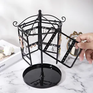 Detail view of rotating black metal jewelry organizer with earrings on a marble surface