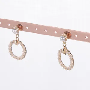 Detailansicht von Perlenohrringen an einem roségoldenen Schmuckständer aus Metall
