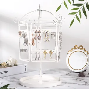 Close-up of a white rotating earring stand with multi-layered hangers and tray base