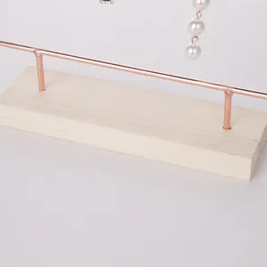 Makro-Detail des Holzsockels und der rotgoldenen Metallsäule für Ohrringhalter