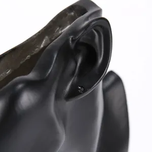 Minimalist glossy black round stud earrings displayed on a black resin ear mannequin
