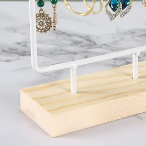 Gros plan d'un support à bijoux en métal blanc avec socle en bois pour boucles d'oreilles