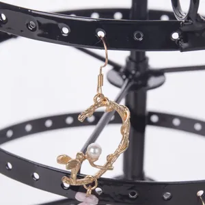 Vintage gold earring with angel detail and pink stone on a rotating display stand