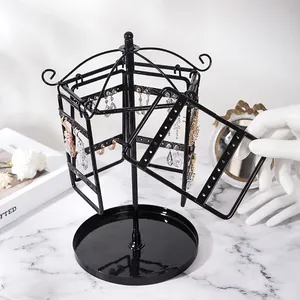 Rotating black metal earring organizer stand on marble surface with vanity items