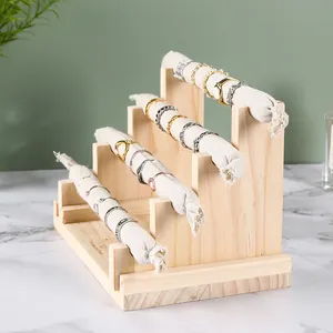 Macro detail of a four-tier wooden jewelry stand featuring light linen rolls for rings