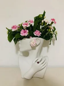 Detail of white ceramic bust vase used as jewelry stand with floral arrangement