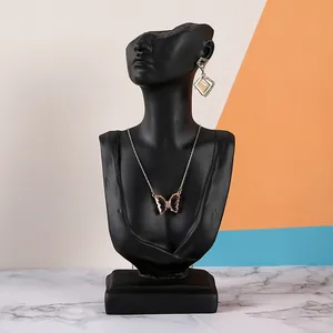Detail of butterfly pendant necklace and geometric earrings on a black bust display stand