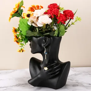 Detail of matte black female bust vase with jewelry display and colorful flowers