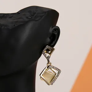 Detail of geometric gold earrings with rhinestones on a black mannequin display bust