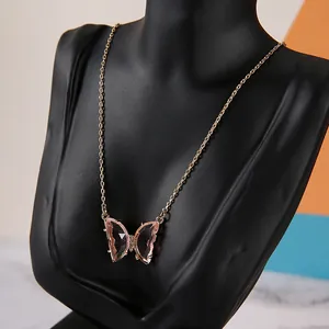 Detailed close-up of gold butterfly pendant with purple resin wings on a black neck bust