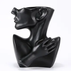 Macro view of matte black ceramic sculpture showing abstract facial profile and hand detail