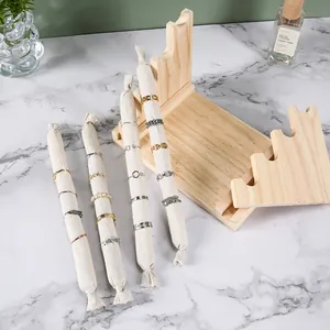 Wooden jewelry display stand with linen rolls showcasing assorted gold and pearl rings