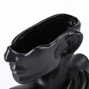 Detail of matte black ceramic abstract portrait stand with smooth texture and sleek finish