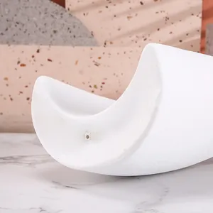 Close-up of white crescent resin ornament with matte texture and hole on marble desk
