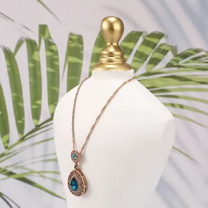 Dettaglio di un busto in resina con collana vintage dorata e pietra a goccia blu scuro