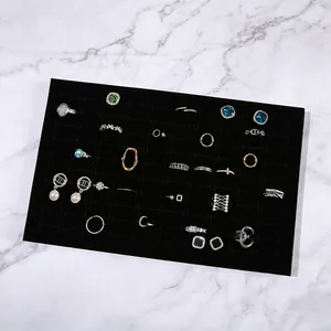 Rectangle black velvet jewelry display tray for rings and earrings on marble background