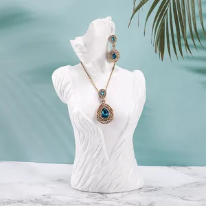 Elegant gold necklace and teardrop blue crystal earrings on white resin mannequin