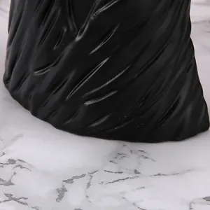 Detailed view of matte black resin bust base featuring fine fabric texture details