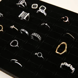 Detail view of assorted gold and silver rings with charms on black velvet display tray