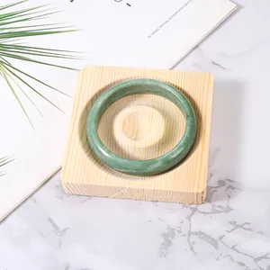 Natürlicher grüner Jade-Armreif auf einem minimalistischen Schmucktablett aus Echtholz