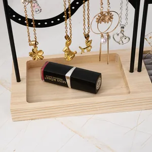 Détail du porte-bijoux avec socle en bois et colliers suspendus sur marbre blanc